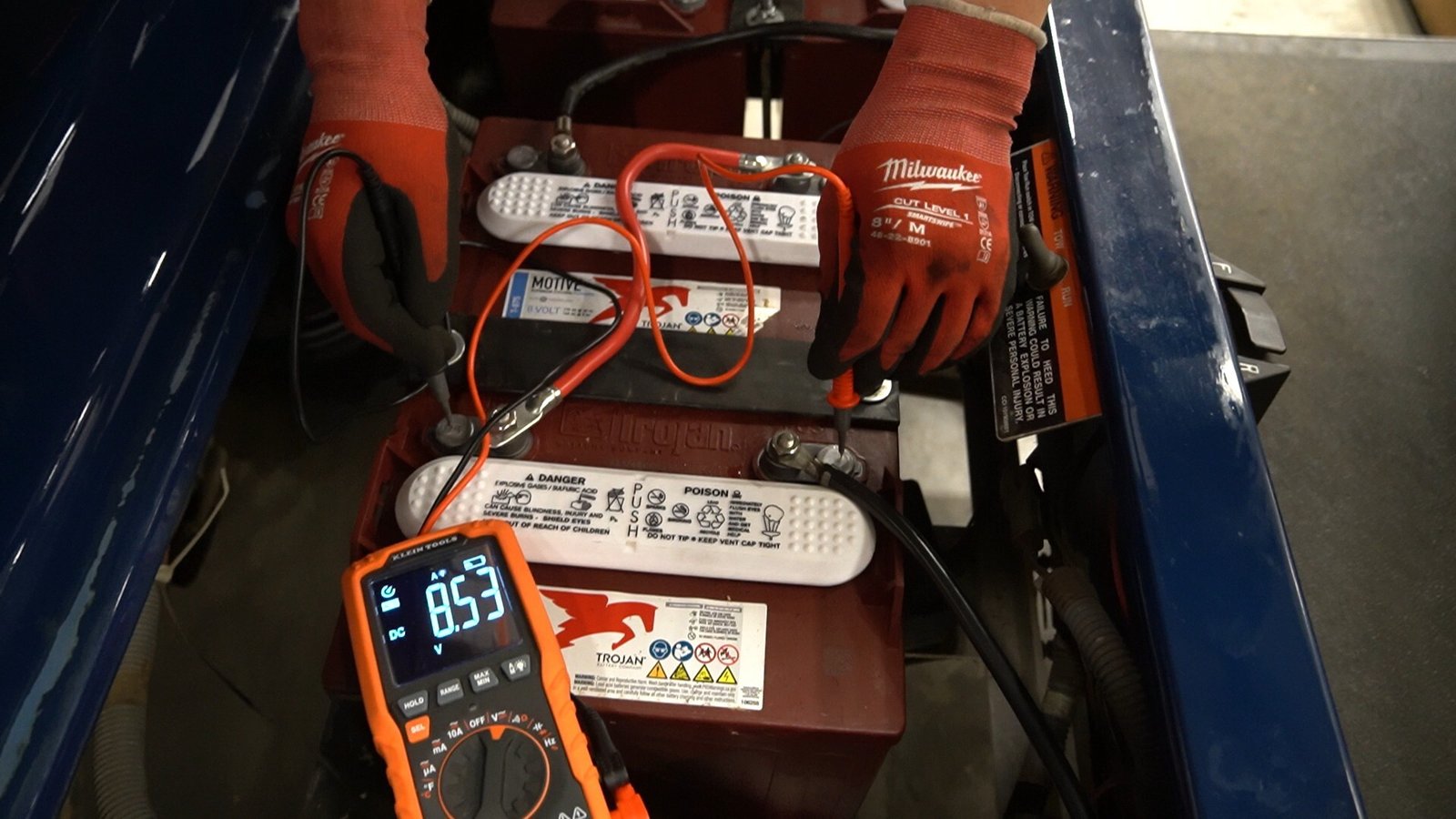 Multimeter reading voltage across a golf cart battery cable during a voltage drop test under load