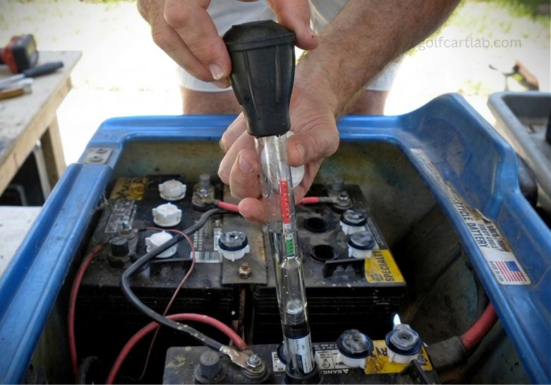 Battery hydrometer pulling an electrolyte sample from a flooded golf cart cell to read specific gravity