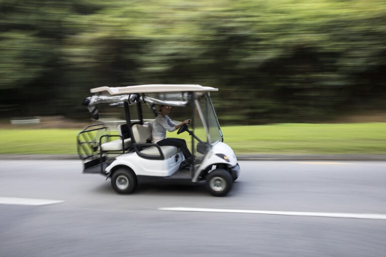Street legal golf cart driving on a road, illustrating golf cart top speed by brand and model